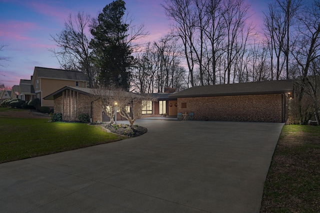 mid-century home featuring driveway, a front lawn, and brick siding