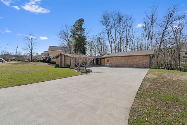 view of front of property featuring a garage, brick siding, driveway, and a front lawn