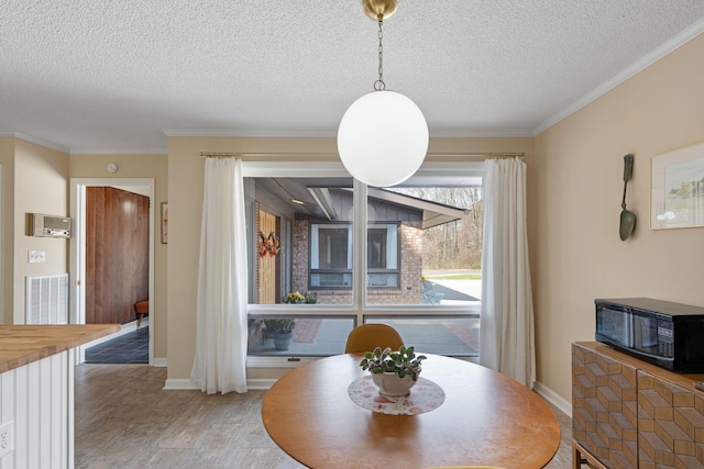 dining area featuring a textured ceiling, ornamental molding, visible vents, and baseboards