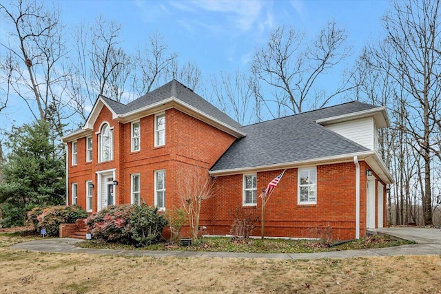 view of home's exterior featuring an attached garage, brick siding, driveway, roof with shingles, and a lawn