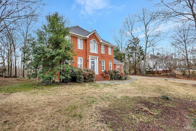 colonial house featuring a front yard and brick siding