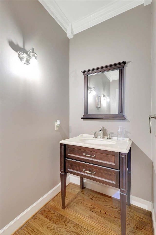 bathroom featuring crown molding, vanity, baseboards, and wood finished floors