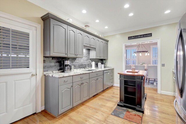 kitchen featuring crown molding, decorative backsplash, gray cabinetry, appliances with stainless steel finishes, and light wood-type flooring