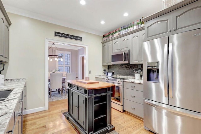 kitchen with gray cabinets, decorative backsplash, stainless steel appliances, and crown molding