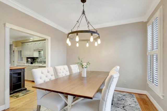 dining area with baseboards, crown molding, and light wood finished floors