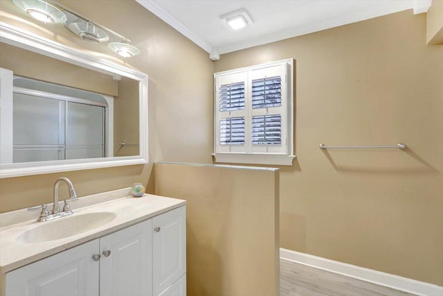 bathroom featuring baseboards, wood finished floors, crown molding, and vanity