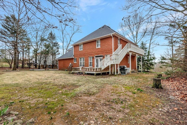 rear view of property with a yard, a wooden deck, stairs, and brick siding