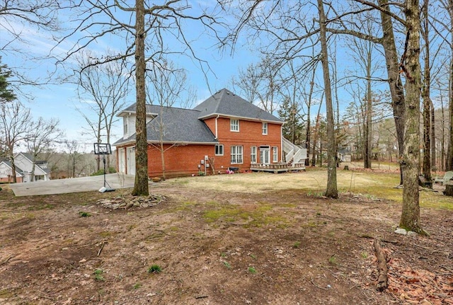 back of house with a garage, brick siding, driveway, and a deck