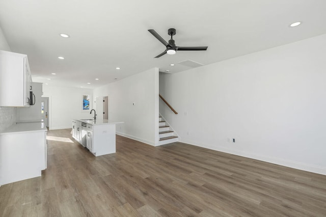 kitchen featuring dark wood-type flooring, a sink, a kitchen island with sink, and white cabinets