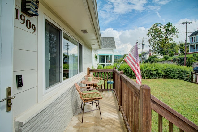 wooden terrace with covered porch and a lawn