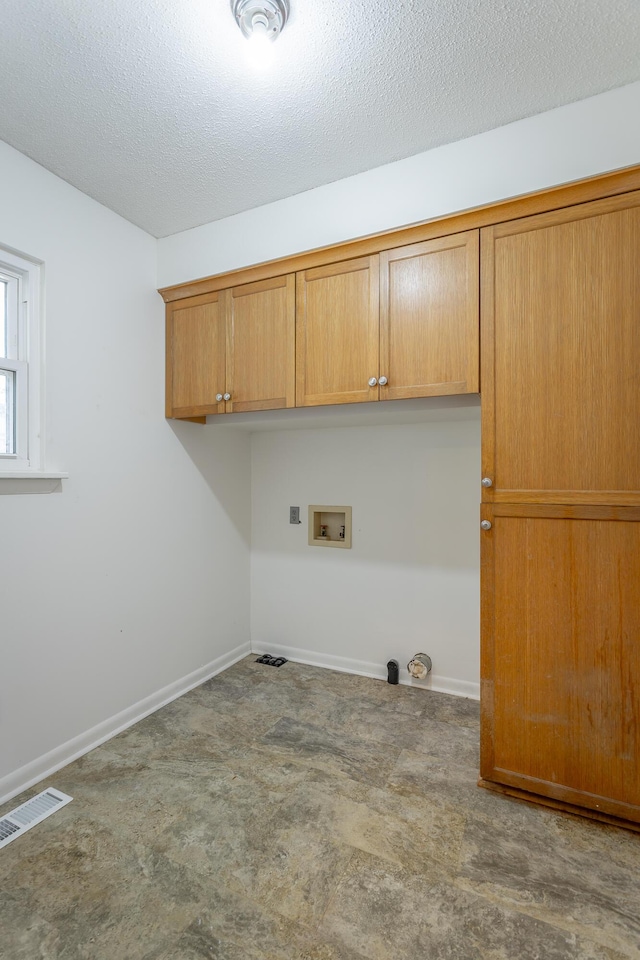 laundry area featuring visible vents, cabinet space, a textured ceiling, and baseboards