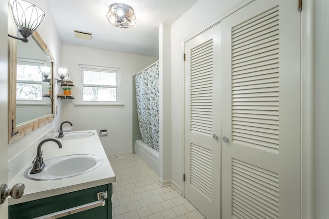 full bath featuring a sink, a closet, double vanity, and tile patterned flooring