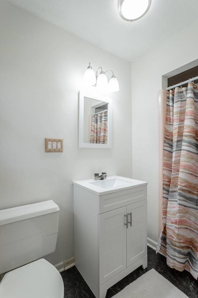 bathroom featuring vanity, toilet, baseboards, and a textured ceiling