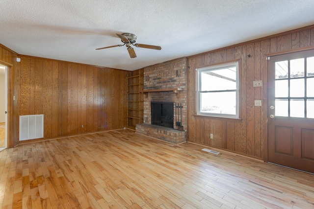 unfurnished living room featuring visible vents, a fireplace, a textured ceiling, and hardwood / wood-style flooring