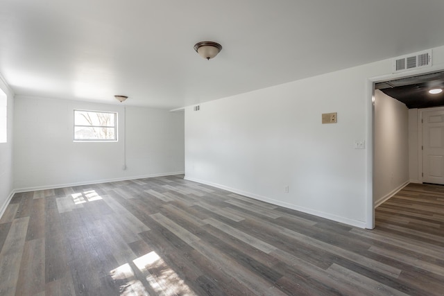 unfurnished room featuring visible vents, baseboards, and dark wood-style flooring