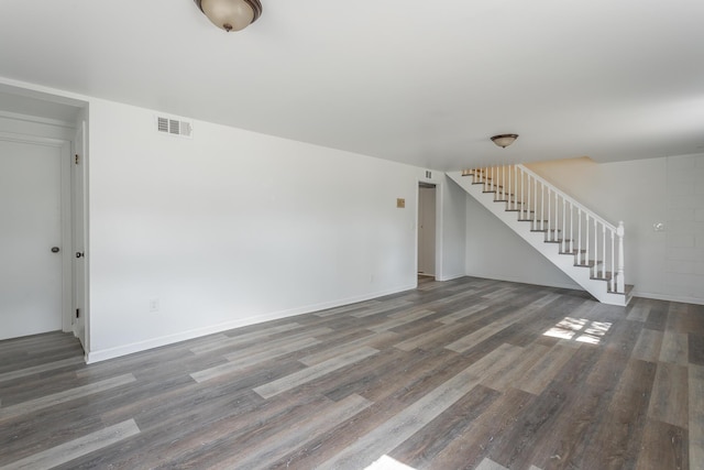 unfurnished living room with stairs, wood finished floors, visible vents, and baseboards