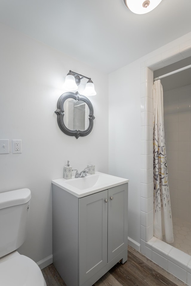 full bathroom featuring toilet, wood finished floors, a shower stall, baseboards, and vanity