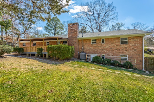 rear view of property featuring brick siding, fence, central AC unit, a chimney, and a yard