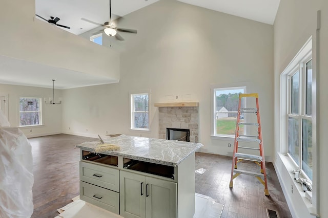 kitchen with light stone counters, a fireplace, open floor plan, wood finished floors, and high vaulted ceiling