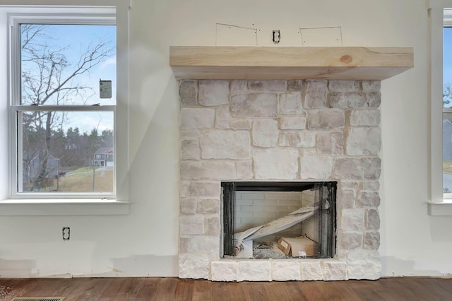 room details with a stone fireplace and wood finished floors