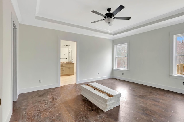 unfurnished bedroom with hardwood / wood-style flooring, multiple windows, baseboards, and a raised ceiling