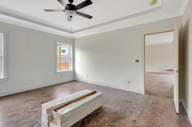 unfurnished room with ceiling fan, a tray ceiling, and baseboards