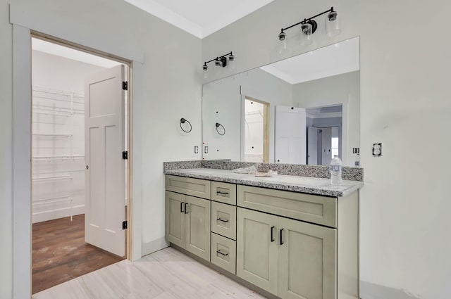 bathroom with double vanity, ornamental molding, and a walk in closet