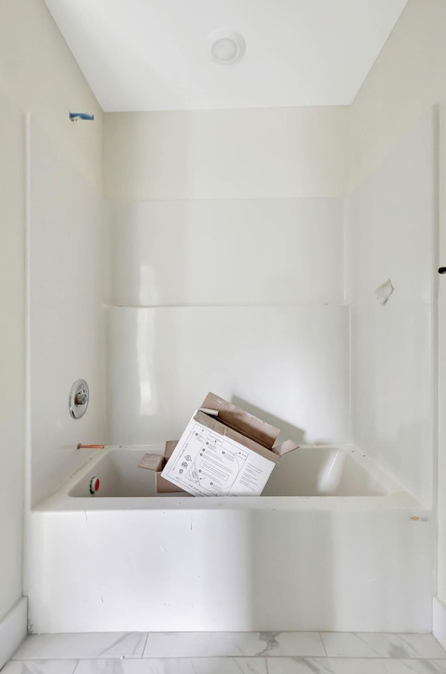 bathroom featuring marble finish floor and a tub to relax in