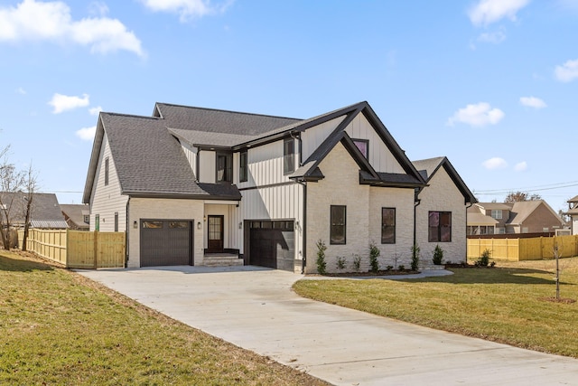 modern farmhouse style home featuring concrete driveway, board and batten siding, a front yard, and fence