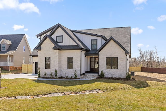 modern farmhouse featuring roof with shingles, a front lawn, board and batten siding, and fence