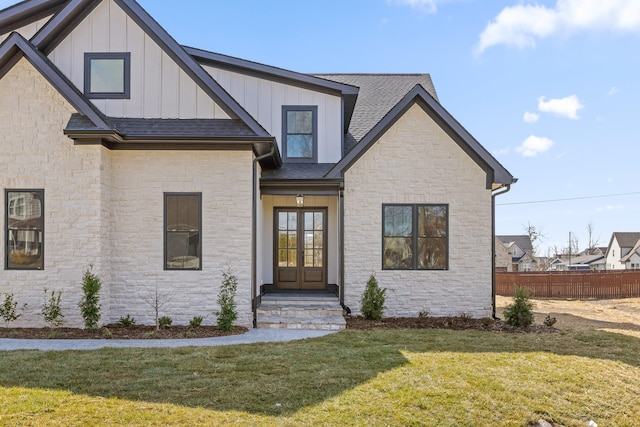 modern farmhouse with a shingled roof, fence, french doors, board and batten siding, and a front yard