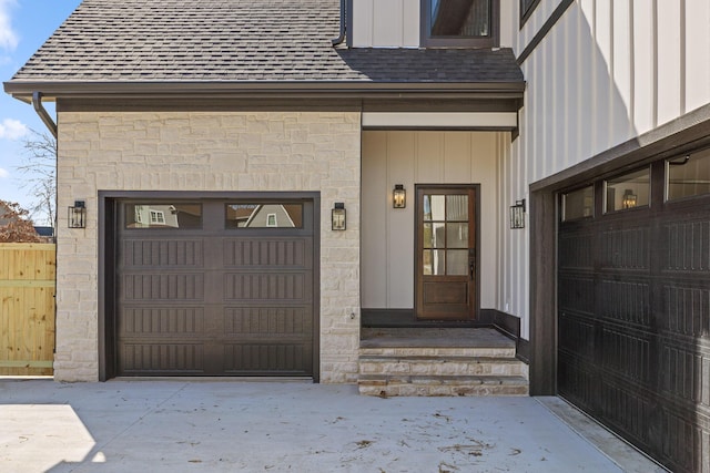 property entrance featuring a garage, stone siding, a shingled roof, and board and batten siding