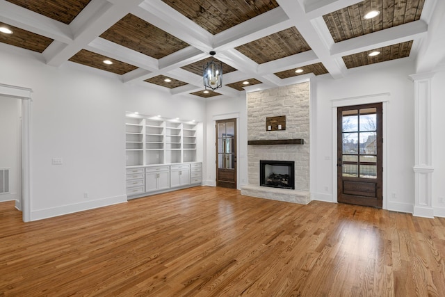 unfurnished living room with baseboards, a fireplace, beamed ceiling, and light wood finished floors