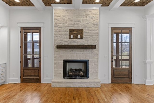 unfurnished living room featuring a stone fireplace, recessed lighting, wood finished floors, baseboards, and beamed ceiling