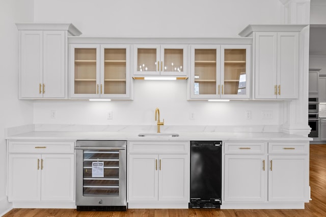 bar with double oven, wine cooler, wood finished floors, a sink, and wet bar