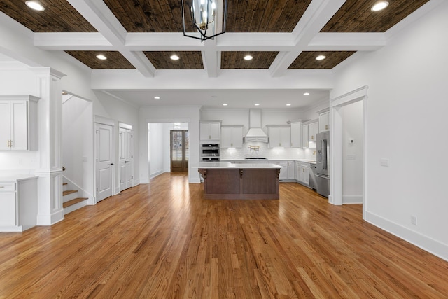 kitchen featuring decorative backsplash, stainless steel appliances, light countertops, light wood-style floors, and premium range hood