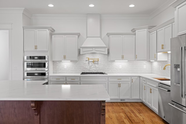 kitchen featuring stainless steel appliances, premium range hood, a sink, and crown molding