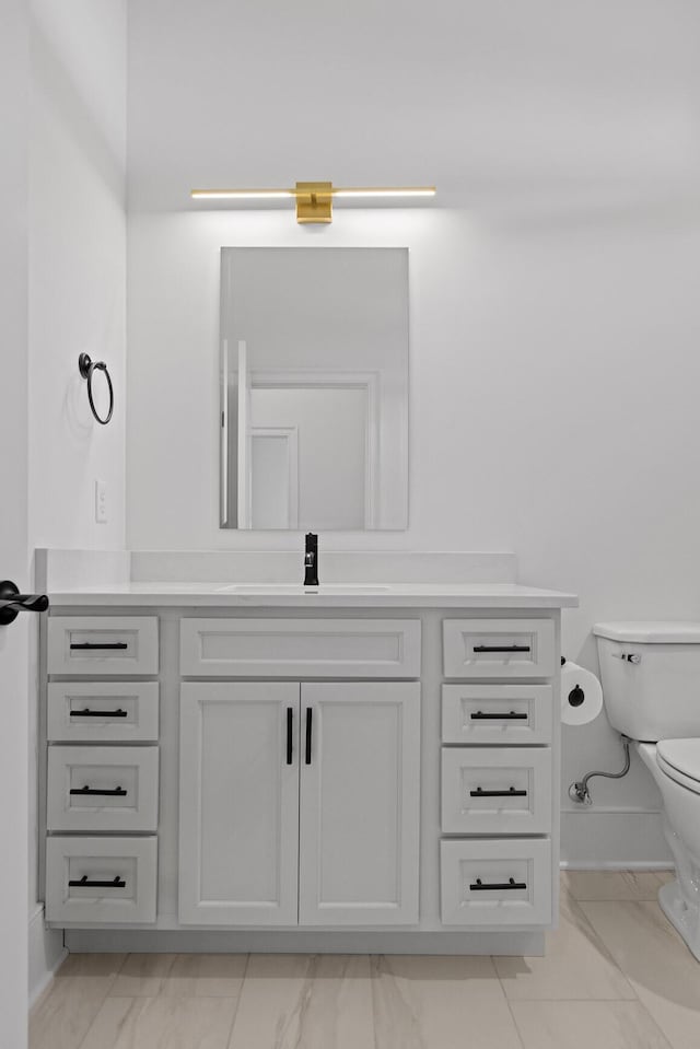 bathroom with marble finish floor, vanity, toilet, and baseboards