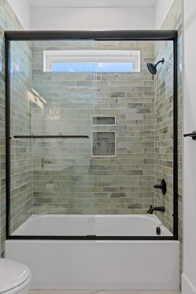 bathroom with a wealth of natural light, toilet, and bath / shower combo with glass door