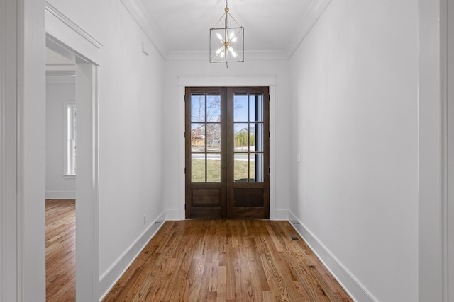 entryway featuring a notable chandelier, wood finished floors, baseboards, french doors, and crown molding