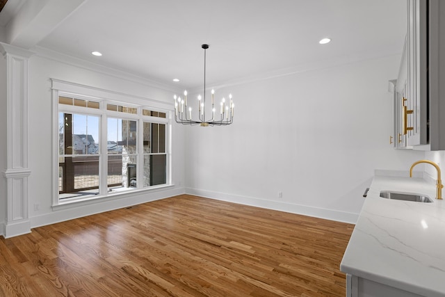 unfurnished dining area with recessed lighting, ornamental molding, a sink, wood finished floors, and baseboards