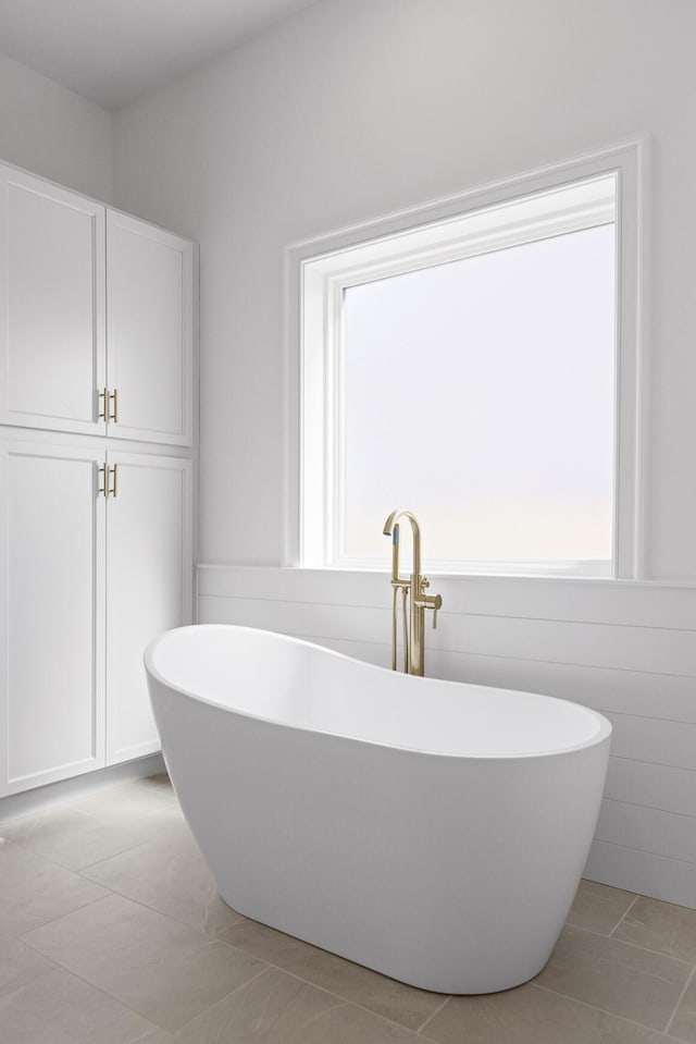 bathroom with tile patterned flooring and a freestanding bath