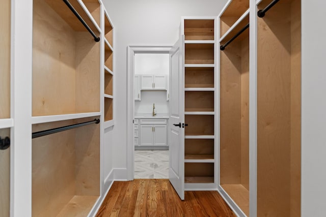 spacious closet with a sink and wood finished floors