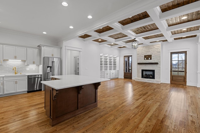 kitchen with appliances with stainless steel finishes, light wood-type flooring, a sink, and decorative backsplash