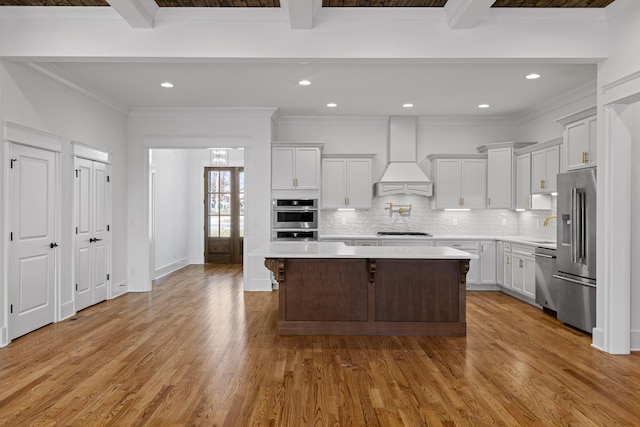 kitchen with stainless steel appliances, light countertops, light wood-type flooring, tasteful backsplash, and custom range hood