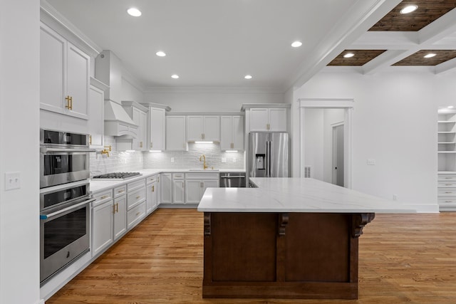 kitchen with light wood-style flooring, a center island, stainless steel appliances, white cabinetry, and a sink