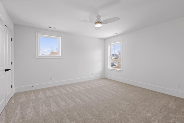 carpeted spare room featuring baseboards, visible vents, and ceiling fan