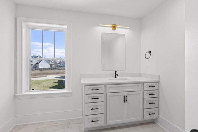 bathroom with baseboards, marble finish floor, vanity, and a healthy amount of sunlight