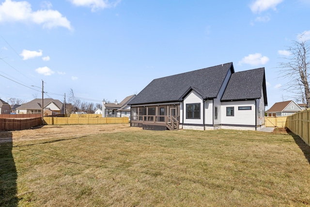 rear view of house with a shingled roof, a lawn, a fenced backyard, and a sunroom