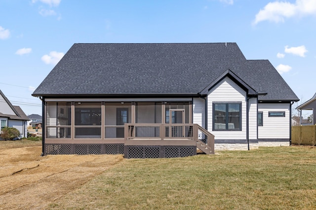 rear view of house featuring a sunroom, a lawn, and roof with shingles